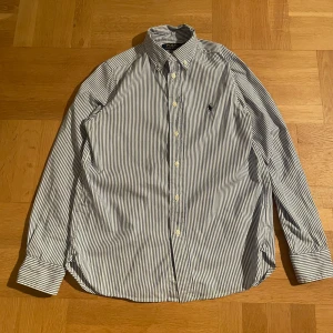 Blårandig skjorta från Ralph Lauren - Säljer en blårandig skjorta från Ralph Lauren  den är i riktgt bra skick förutom att den har två små kaffe fläckar på skjorta men dom syns inte om man har den på. Den är perfekt till sommaren för är lätt att matcha med💛 skriv till mig vid frågor eller intresse 👍🏻💛