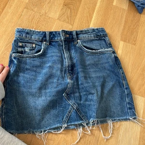 Jeanskjol med fransad kant - Säljer en blå jeanskjol med fransad nederkant, skit snygg 