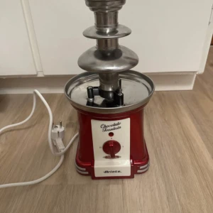 Chokladfontän från Ariete - Säljer en röd chokladfontän från Ariete i retrostil. Maskinen har en blank röd bas i metall och plast, med tre nivåer i rostfritt stål för rinnande choklad. Perfekt för att doppa frukt eller godis. Strömkabel medföljer. Jätterolig och fin chokladfontän från Ariete! Finns knappt att köpa längre och köpt för ca 800 kr och endast använd 2 gånger! Väl omhändetagen och tvättas NOGGRANT innan den skickas!😊