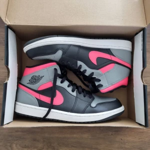 Nike Air Jordan 1 Retro Mid Pink Shadow - Säljer ett par Nike Air Jordan 1 Mid i svart, grått och hot punch rosa.  Har bara använts en gång och är i nyskick!