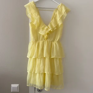Ljusgul volangklänning  - Så fin ljusgul volangklänning från Nelly! Öppen i ryggen och stretchig i midjan 