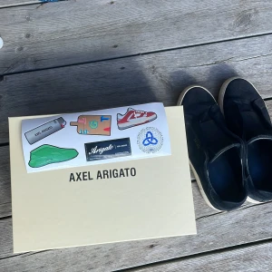 Laceless skor från Axel Arigato - Säljer ett par skor från Axel Arigato, skorna är laceless. Skorna har minimalistisk design utan snörning och är tillverkade i tyg med diskret logga på sidan. Perfekta för en stilren och enkel look.