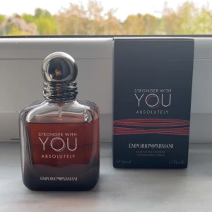 Stronger With You Absolutely Eau de Parfum - En elegant herrparfym från Emporio Armani, Stronger With You Absolutely. Flaskan är mörkbrun med silverfärgad rund kork och stilren design. Doften är intensiv och modern, perfekt för dig som gillar exklusiva parfymer.