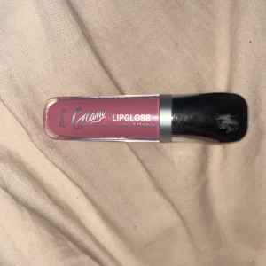 Essence Glam Lipgloss i rosa nyans - Essence Glam Lipgloss i en skimrande rosa färg. Kommer i en kompakt tub med svart och silverfärgat lock. Ger glans och fukt till läpparna med en mjuk applikator. Perfekt för att ge läpparna en fräsch och glansig finish. Har köpt en kiko så jag använder inte den! Knappast använd som man kan se i bild 2!❤️