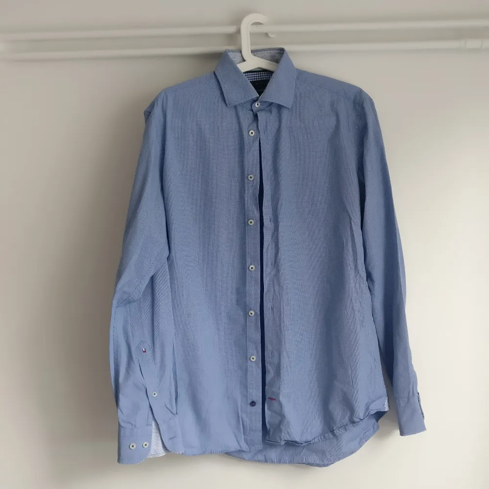 Skjorta från Tommy Hilfiger i bra skick. Ljusblå med smårutigt mönster. Bra finskjorta eller jobbskjorta. Köparen står för frakt.. Skjortor.