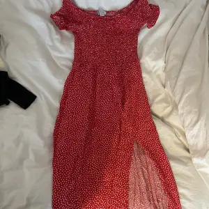 Lång vitblommig röd klänning går att ha Offshoulder eller över axlarna. Med slits på vänsterben 