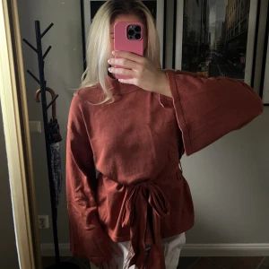 Stickad tröja - Supermysig stickad tröja med band som knytes i midjan. Kopparfärgad med slits i ärmarna och sidan. Storlek M, använd fåtal gånger, gott skick. 🧡