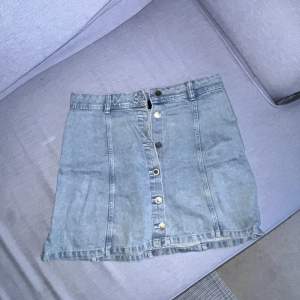 En a-linjeskuren kjol i jeansmaterial och uppknäppbara knappar i mitten. Använt skick💘