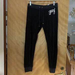 Juicy Couture mjukisbyxor - Svarta mjukisbyxor ifrån märket Juicy Couture. Loggan är lite sprucken och det finns en liten brun fläck, annars är det bra skick. Jag säljer dessa då de är för korta för mig.