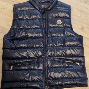 Moncler Väst - Hej!  Säljer min Moncler Väst då den inte passar mig längre. Västen är i Storlek L (52) och är i ett mycket fint skick. Använd i cirka 1 år.