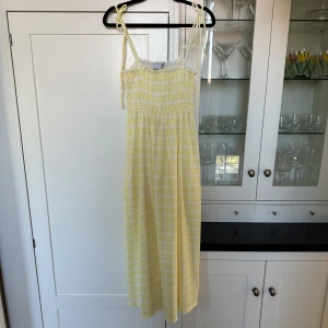 Ginghamrutig klänning i gult, ASOS design, 36 - Gul midiklänning med ginghammönster. Smockad överdel och tunna axelband som går att justera genom att knyta dem. Nypris ca 400. Använd en gång😊