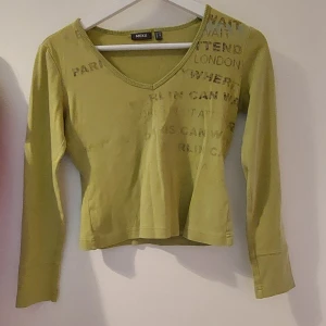 Grön långärmad tröja - Grön långärmad tröja, ganska kort. Tryck på framsidan, en del av det syns inte så mycket. 