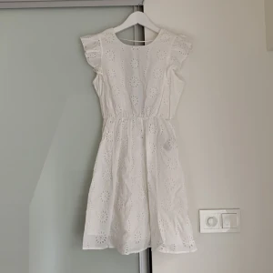 Vit sommarklänning med öppen rygg - Säljer den här vita sommarklänningen från Vero Moda med hålbroderier och öppen rygg! Den är helt oanvänd och ordinarie priset är 500kr men säljer för 375kr!