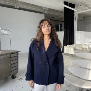 Design by Sí kappa - En kappa fårn design by Sí i färgen naevy men jag tycker den mer åt åt det svarta hållet. Byter helst mot en svart i xs/s men säljer också för bra pris då den är ny. 