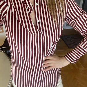 Blus  - Vit/vinröd randig blus från h&m. Super fint skick, 100% polyester men känns väldigt skön att ha mot kroppen, mer som viskos.  Storlek 34, men är lite oversized i modellen så passar även 36.