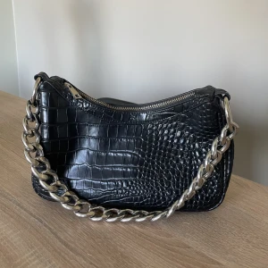 Svart väska med mönster - Knappt använd väska. Silver kedja. Får plats med mycket, perfekt i sommar