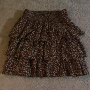 En brun blommig kjol från Lindex i storlek 158-164. Det är en liten fläck på sidan som knappt syns. En liten del av tråden på en av volangerna är borta men sytt igen så den inte går upp ännu mer.Säljer den för den inte kommer till användning längre.😍