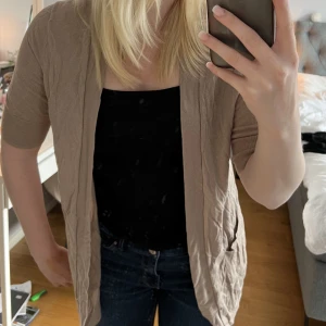 Beige kofta strl M - Mörk beige kortärmad kofta, slutar mitt på rumpan med fickor på sidan. Skriv vid frågor och fler bilder💓