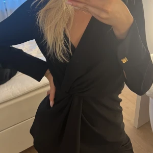 Topp från Zara - En jättesnygg svart topp från Zara med låg skurning framtill och dragkedja i sidan. Snygga knappdetaljer på ärmen.