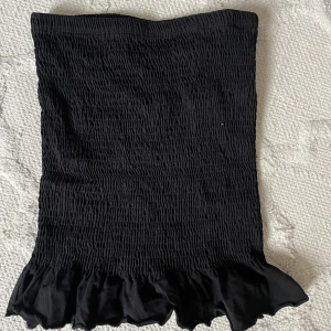 Smockad svart kjol - Smockad svart kjol med en liten volang. Från Gina tricot. Stl XS. Skriv för fler frågor eller intresse 