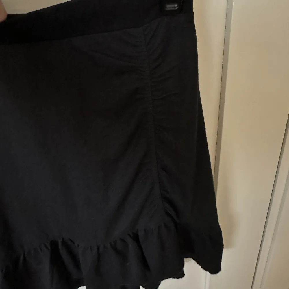 svart kjol med scrunch detalj och volanger, sitter relativt tajt. Kjolar.