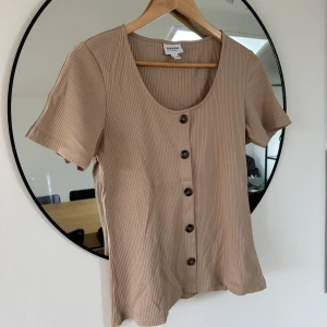 T-shirt vero moda - Oanvänd beige T-shirt från Vero Moda med knappar framtill.  