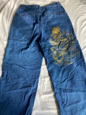 Loose Fit Jeans - Baggy jeans med en guld drake på baksidan av de. Skulle säga att de passar allt från 34 till 38 