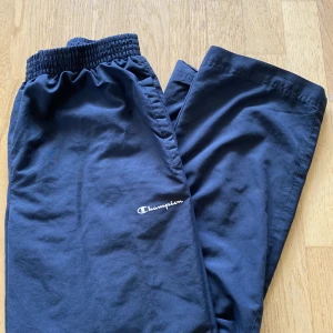 Trackpants - Snygga trackpants / träningsbyxor från Champion. Har en fläck längst ner på ena benet och en liten slitning på andra, men utöver det är de i gott skick! Passar mig som är 160cm🌟