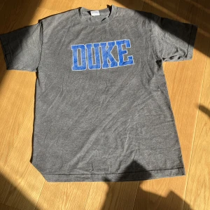 Vintage T-shirt - Grå vintage t-shirt med blått tryck, 50% bomull och i storlek L