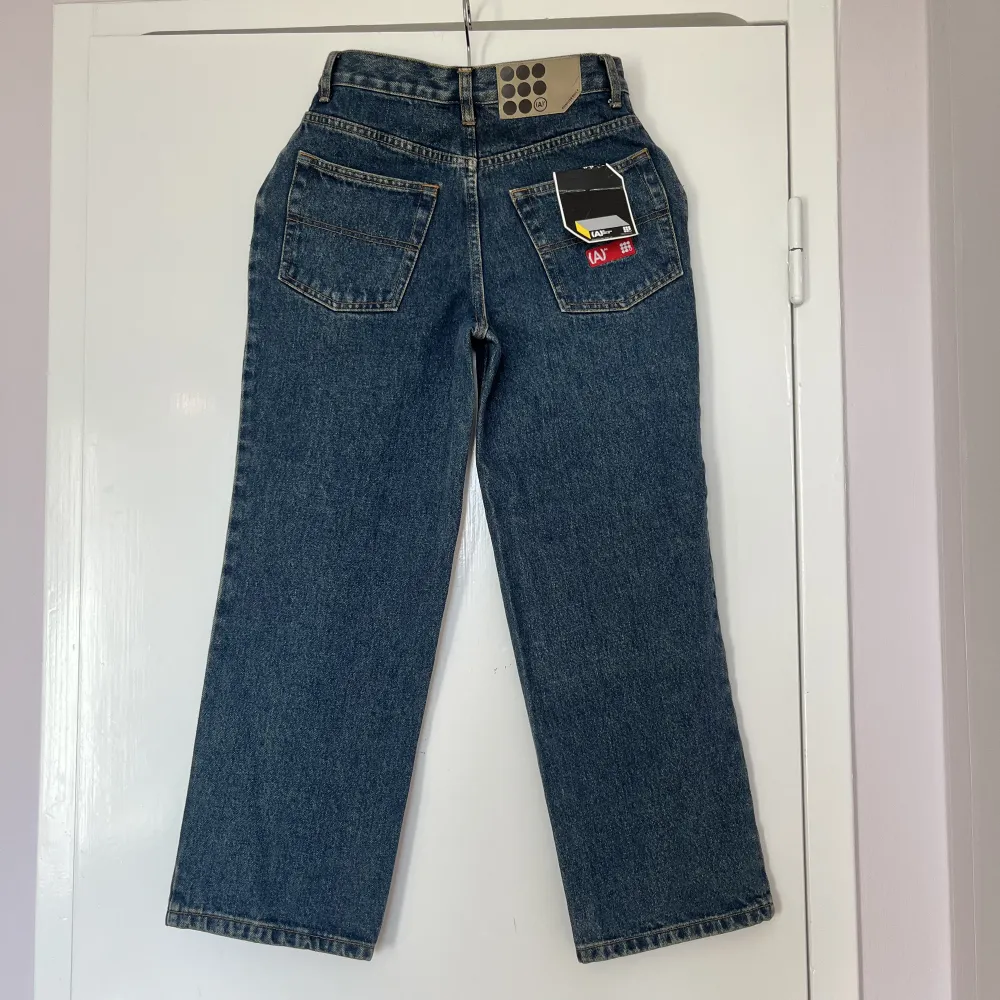 Blå jeans med röda detaljer från AM. Raka och mid-waist. Nyskick (prislapp kvar!). Innerbenslängd ca 68cm, Grenhöjd ca 25cm, midjemått ca 68cm. Jag är S och 175cm lång och de är för små på mig. . Jeans & Byxor.