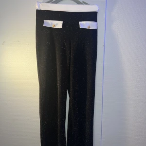 Glittriga byxor med guldknappar stl XS/S - Svarta diskret glittriga byxor med guld knappar. Stl XS/S. Säljes för 100kr