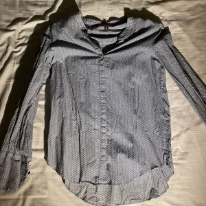 Mönstrad Blus/skjorta Hugo Boss - Olika nyanser av blått formar ett vackert mönster av hexagoner. Vackra knappar på armslutet.