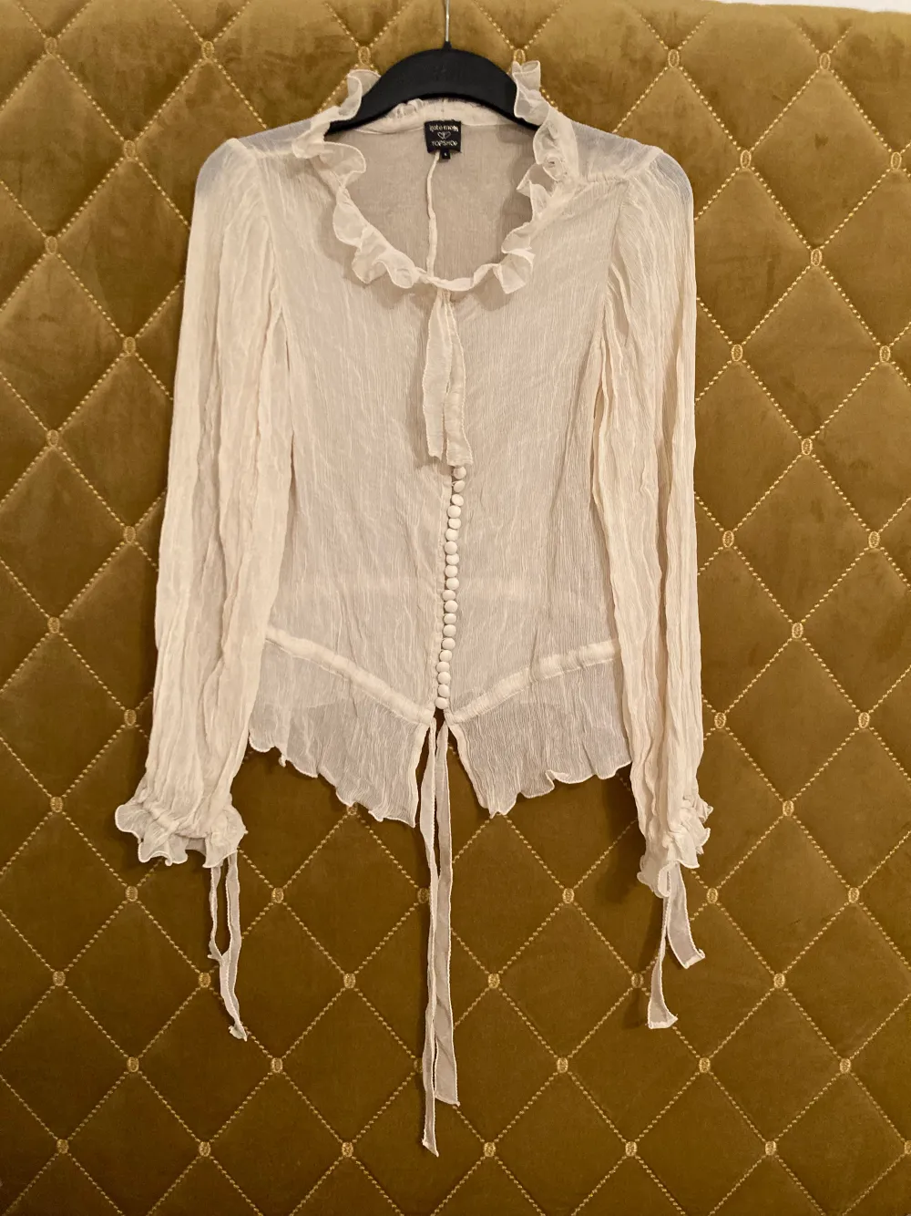 Blus i 100% silke från topshop i samarbete med Kate Moss, genomskinlig, beige. Strl S (väldigt lite i storleken, mer som XS) aldrig använd men säljer billigt eftersom ugglorna som håller knapparna är små gummiband och några av dom har töjts ut (pga tiden). Blusar.
