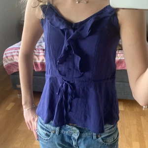 Volangtopp  - Jättesöt mörkblå topp med volang längs kanten, knappar och med ett justerbart band i midjan💙Axelbanden är också justerbara🙌