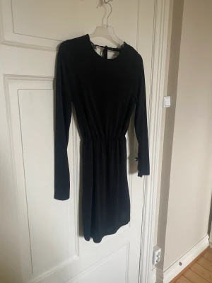 Klänning från Gina Tricot  - Säljer denna snygga klänningen från Gina Tricot. Storlek M. I fint skick. Djup i ryggen, snygga detaljer! Resårband. Långa ärmar. Knytning baktill. 