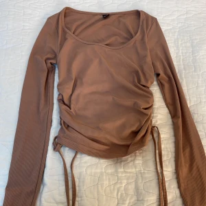 Dammrosa/beige tröja - Aldrig använd. Har snöre på sidorna men går inte att dra i utan ba knytas.