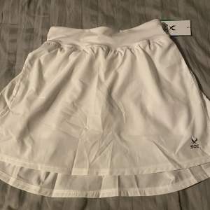 Vit padel/tennis kjol, från märket soc. Strolek 158-164, finns snöre och under short med bollficka. Helt nya med lapp kvar säljer på grund av att jag har en likadan redan sen innan. Nypris 299 kr