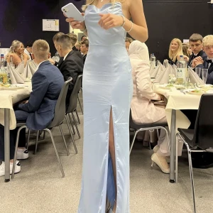 Balklänning - Säljer min balklänning med waterfall slit, endast använd en gång. Går ner till golvet på mig som är 170cm. Dragkedja i ryggen och korsade axelband i ryggen 