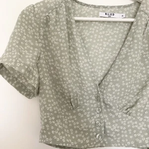Blus  - Gullig grönblommig blus från NAKD. Aldrig använd då jag köpte två storlekar men glömde lämna tillbaka (har lappen kvar). 
