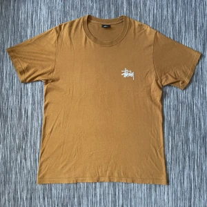 Stüssy T-shirt - Brun Stüssy T-shirt i storlek medium. Loggan på ryggen är lite sprucken (sista bilden) men förutom det är den i mycket bra skick.