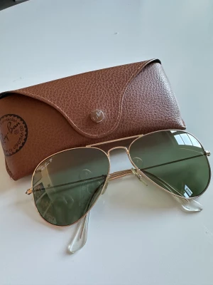 Rayban aviator - Klassikern Rayban aviator i Raybans originalglas (mineralglas). Polariserat, grönt glas, storleken är large metal 58x14. En liten reva på baksidan av fodralet. Putsduk ingår självklart. Använda få gånger, i väldigt fint skick utan skavanker. 😎