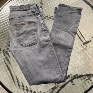 Grim tim nudie - Tjena, säljer dessa grå jeansen från nudie, modell: grim tim. Bra skick bortsett från en liten flaw på ena benet, inget man tänker på vid användning. Står l34 på tagen men sitter som en l32. Tveka inte på att hör er vid ev frågor!