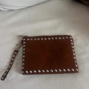 Skitball clutch med silvernitar i en vinröd/brun färg från Gina Tricot. 