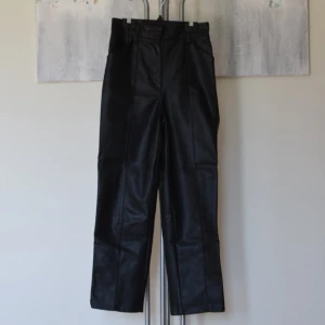 Skinnbyxor  - Märke: H&M Strl: 34 (true to size)  Mått: benlängd innersöm 66cm, midja 64cm, benöppning 18cm Modell: hög midja, raka ankellånga ben (är 168cm som referens på benlängd)  Skick: Använt skick  Material: skinnimitation, 100% polyester