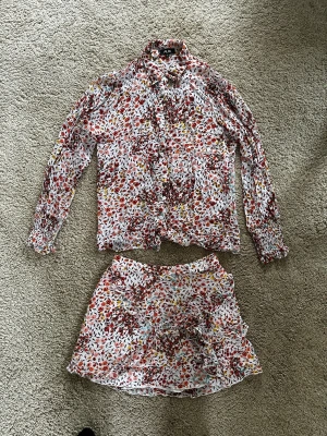 Kjol och blus - Ett jättefint set med kjol och blus i stretchigt material. Kjolen har volanger. 