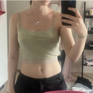 Grön topp - Grön ribbad topp med spetsdetaljer i storlek XXS men passar upp till S skulle jag säga. Lappen inuti har blivit lite avnött, se sista bilden
