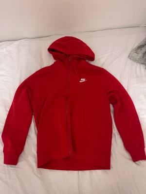 Röd Nike zip hoodie - Säljer min röda Nike hoodie som är nästan helt oanvänd, så den är i väldigt bra skick! Den är storlek M men är lite större i storleken! Säljer för 400kr men pris kan diskuteras vid snabb affär!!!Skriv om du har några frågor!