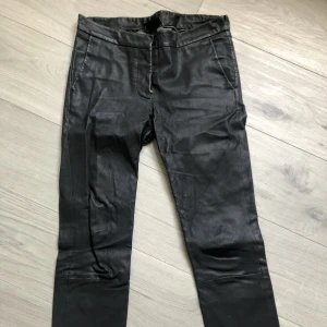 Skinnbyxor i äkta läder DAY strl 36 - Svarta byxor i äkta läder, smal/rak modell från Day Birger et Mikkelsen. Strl 36. Vissa repor och slitna vid rumpan. Hål i innertyget vid grenen.