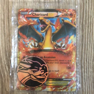 Charizard Pokémon kort - Detta är ett charizard pokemon kort. Det är inte psa10 men är ändå värd att köpa. Det kommer med en trade token och ett plast skydd som skyddar kortet. Kortet är äkta och är i okej skick. Ha en bra dag!