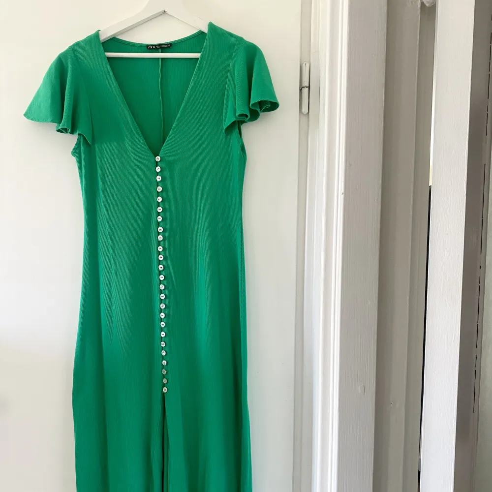Långklänning i härlig grön kulör från Zara! Knäppning längs hela framsidan som sedan skapar en vacker slit nedtill. Volanger som lägger sig fint över axlarna. Klänningar.